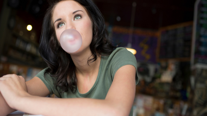 Portrait of teenage girl blowing bubblegum in coffee house