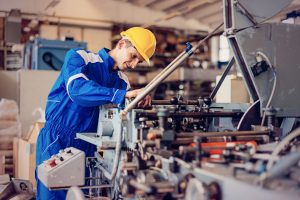 Maintenance engineer or blue collar worker working in production factory, testing and repairing machines, testing roll bars and using grinder or drill.